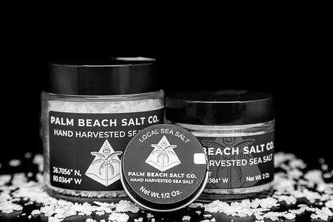 Professional product photography in South Florida by Minnerly Media, showcasing three high-end salt containers on a black backdrop with scattered salt