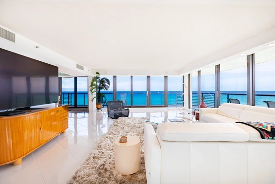 A modern bright white living room with a panoramic view of the blue ocean on the beach in Delray