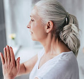 An older woman holding her arms together in a yoga pose