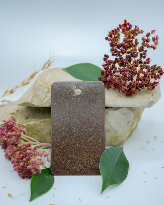 Limestone rocks with red flowers around them and a brown vinyl color sample leaning against the rocks.