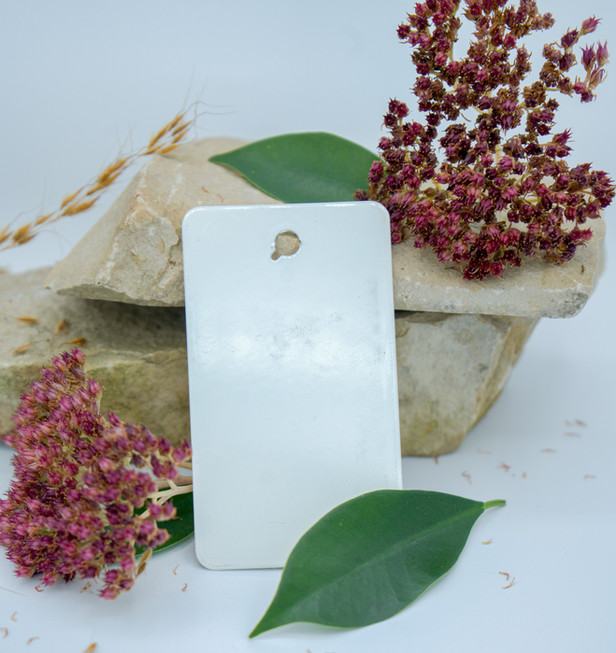 Limestone rocks with red flowers around them and a shiny white vinyl color sample leaning against the rocks.