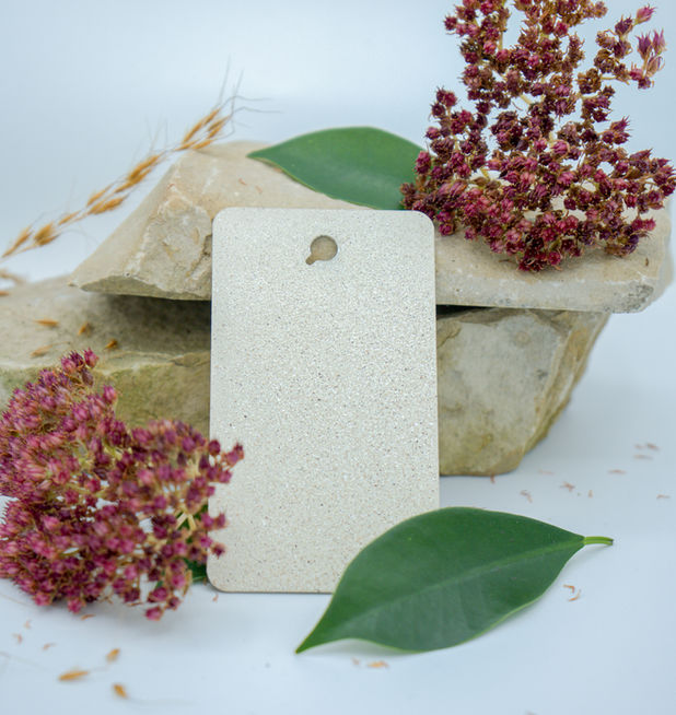 Limestone rocks with red flowers around them and a light vinyl color sample leaning against the rocks.