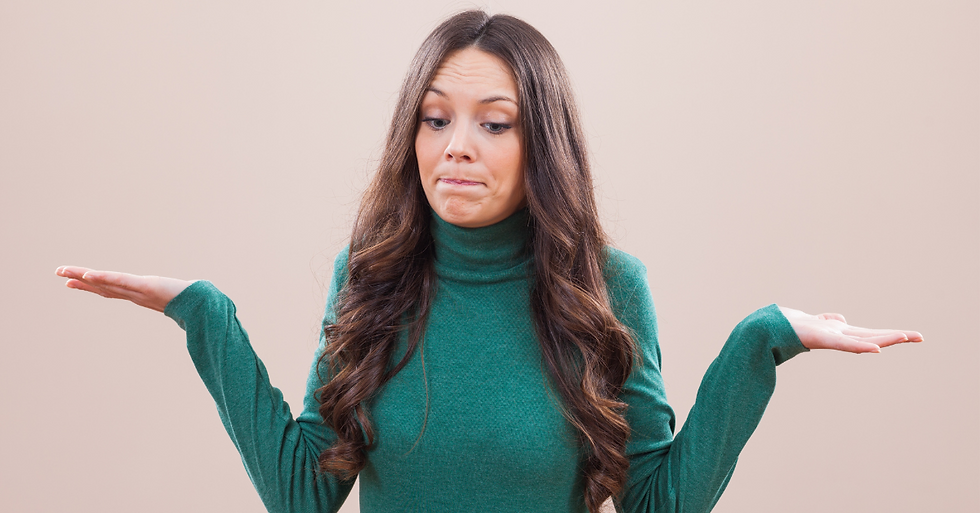 Woman in green sweater shrugging with uncertain expression, symbolizing confusion or indecision about choosing between a dentist and oral surgery