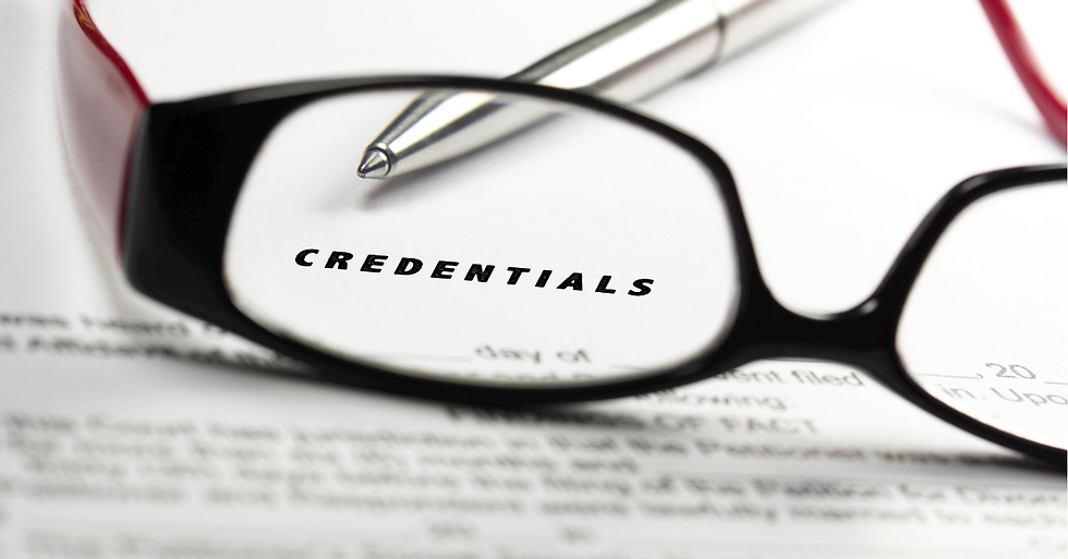 Close-up of eyeglasses focusing on the word 'CREDENTIALS' printed on a document, with a pen resting on the paper in the background.