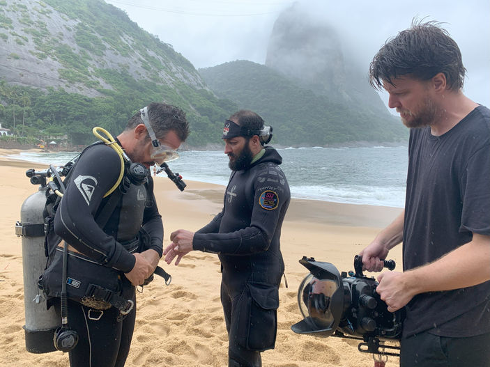 Aquatic film crew preparing underwater camera and diving equipment during a beach shoot in Rio de Janeiro.