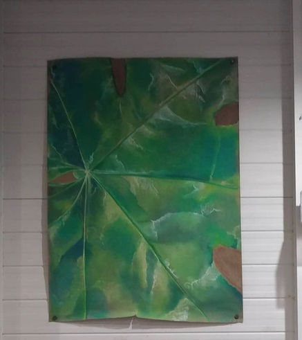 A drawing of a vibrant green leaf with white and yellow highlights on brown paper.