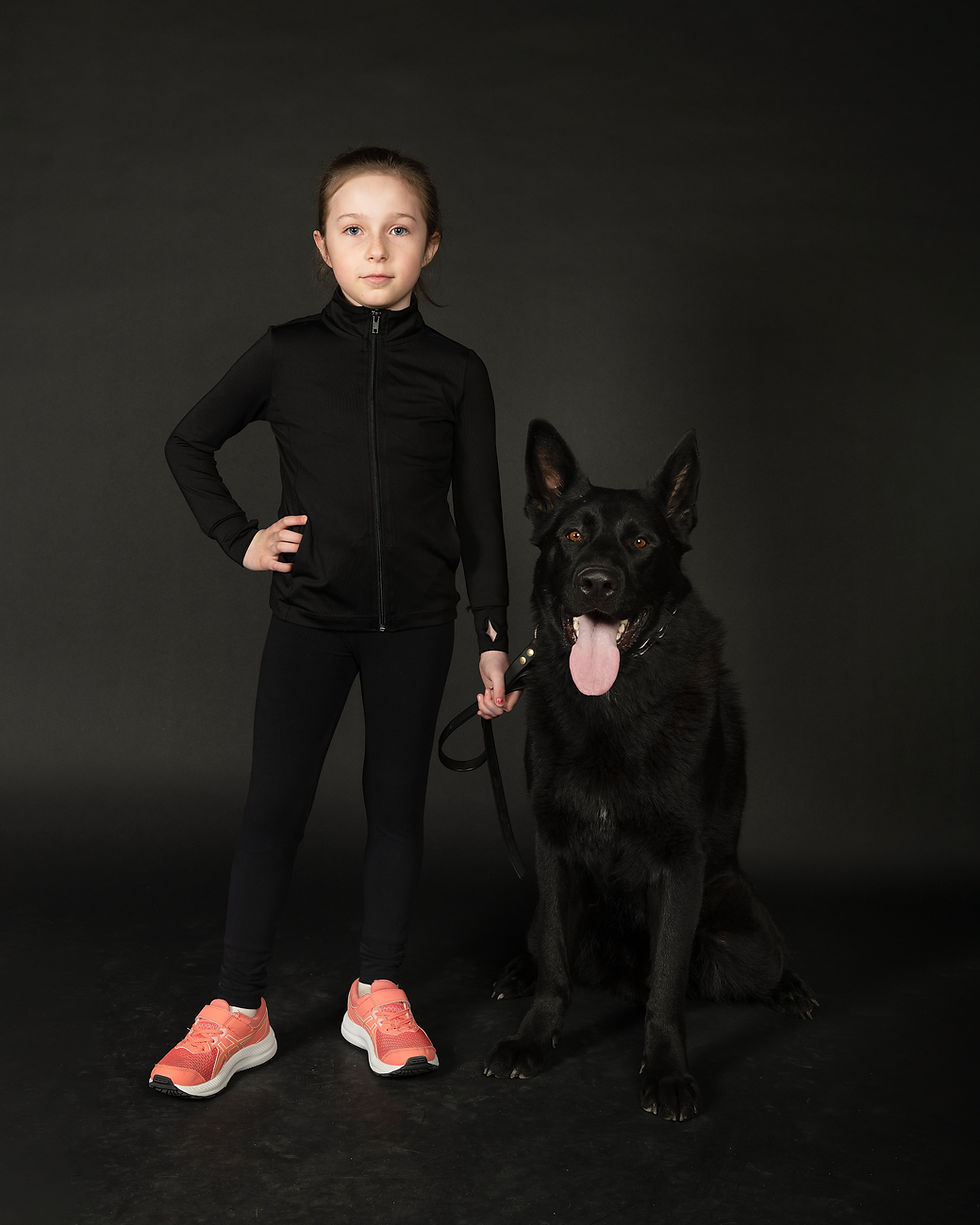 Young girl in black posing with a black German Shepherd.