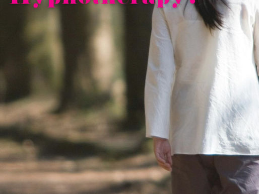 Woman with long black hair, long white shirt, dark trousers and bare feet walking through a sunlit forest path, surrounded by tall trees and greenery, conveying tranquility. Find new pathways