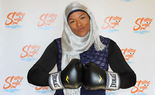 “DeAnn Williams wearing boxing gloves and posing confidently, representing Sisters Sweat Spot Fitness personal training