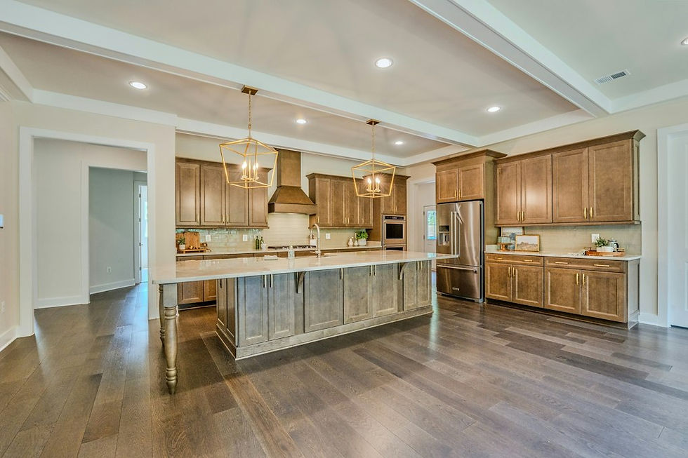 Kitchen with a large quartzite island, brass lantern pendants, double wall ovens, and a range hood in a Carrington home