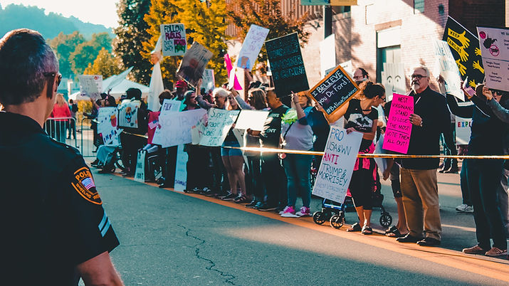 protesters fill the streets with signs that say "brace yourself, novemeber is coming and " I believe you dr. ford #believe survivors"