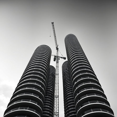 This is a dramatic black-and-white photograph showing several tall, cylindrical skyscraper