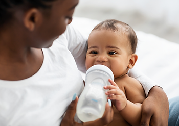 Een baby in de armen van zijn moeder die een flesje vasthoudt