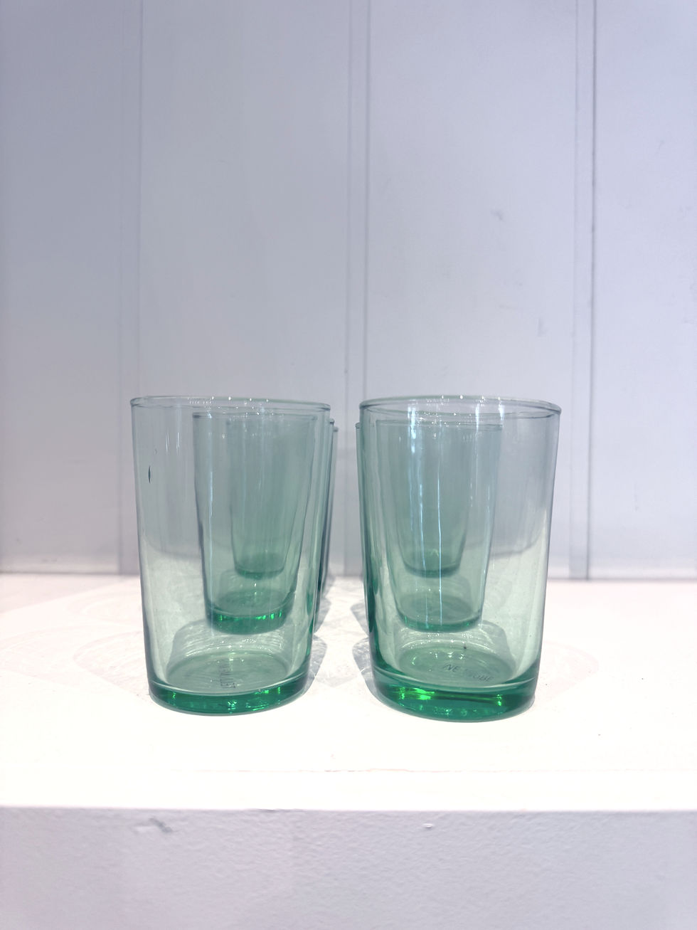 Set of eight handcrafted green glass tumblers made from recycled glass.