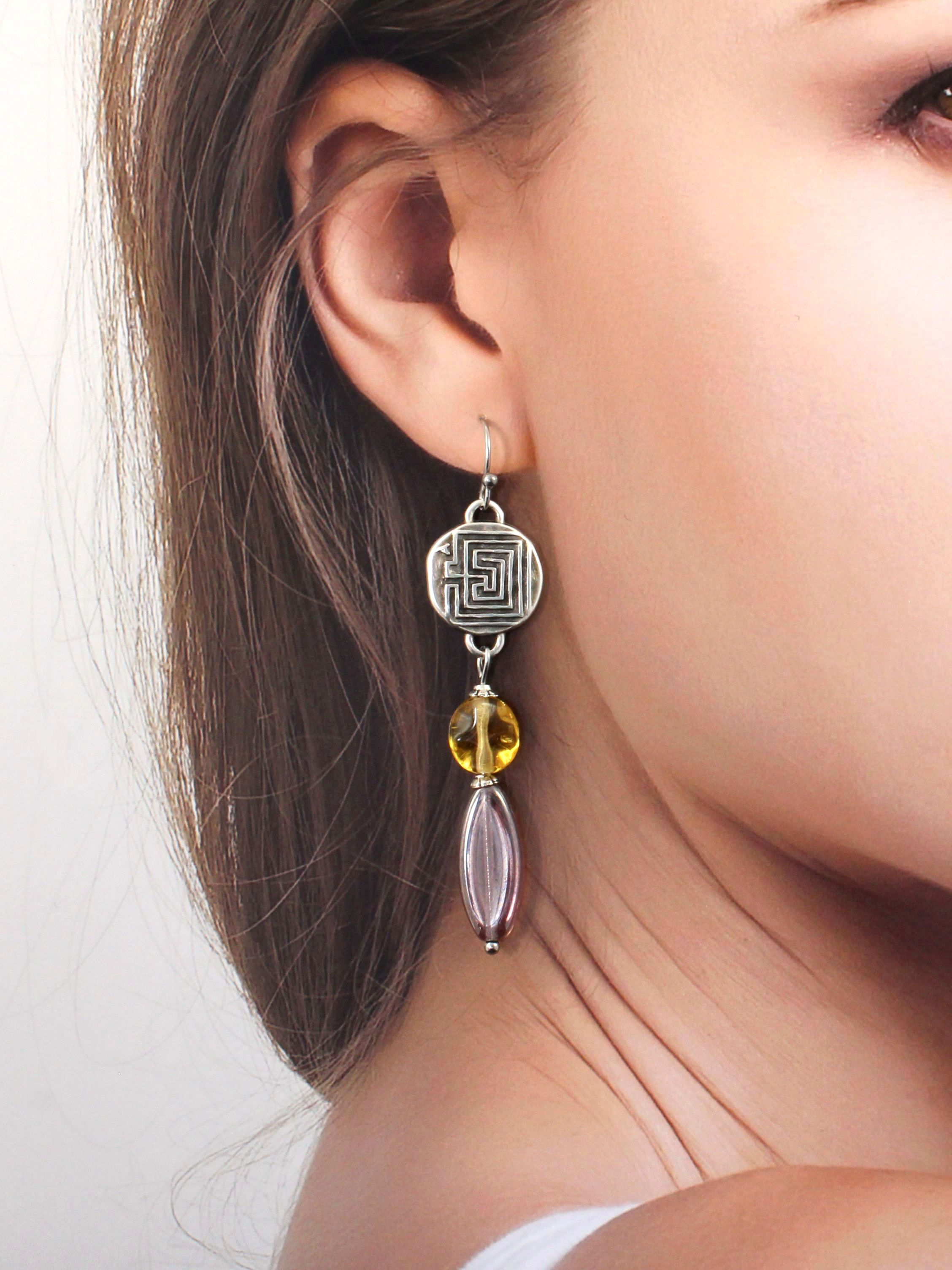 Jeune femme brune portant des boucles d'oreilles CS Atelier en acier plaqué argent inspirées par la Grèce antique