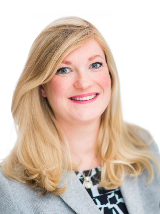 a blonde woman wearing a grey suit staring into the camera. the background is white and taken at a Future Proof studios in Bristol