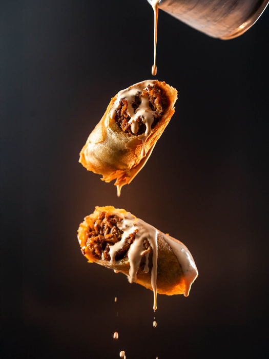 Pastry cut in half in mid-air, sauce being poured onto it by food photographer based in Bristol