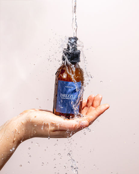 a woman's hand holding a bottle of plantmade skincare. There is water pouring over the product. Shot at Future Proof Studios in Bristol 