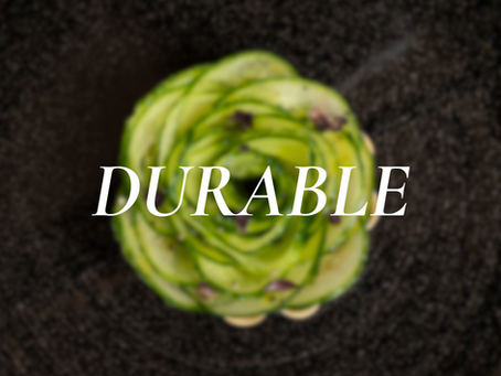 Assiette noire contenant une création culinaire en rosace de légumes verts, avec le mot “DURABLE” inscrit au centre.