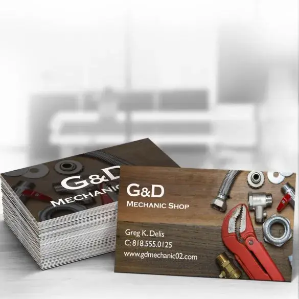 Business cards for G&D Mechanic Shop with tools and hardware on a wooden surface.

