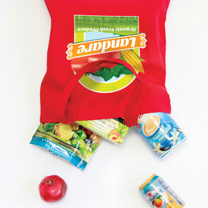 A vibrant red tote bag featuring a logo and filled with snacks, with additional snack items scattered around it.
