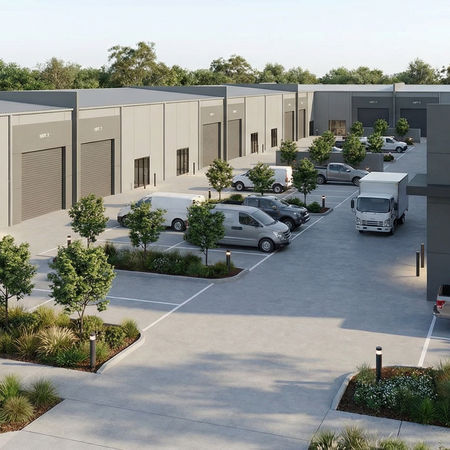 Modern light industrial complex featuring two parallel rows of identical warehouse units with a consistent rectilinear form, large roller doors, and pedestrian entries. The central driveway is framed by structured landscaping, including low plantings and small trees, creating a clear circulation spine between the buildings. The design emphasises functional access, modular repetition, and efficient site organisation within a broader industrial precinct.