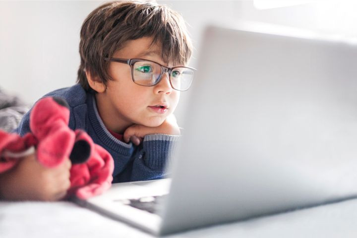 A little boy wearing glasses and holding his fav stuffed animal. He is on a computer doing online child counseling with his therapist. Marble Wellness offers virtual therapy for kids.