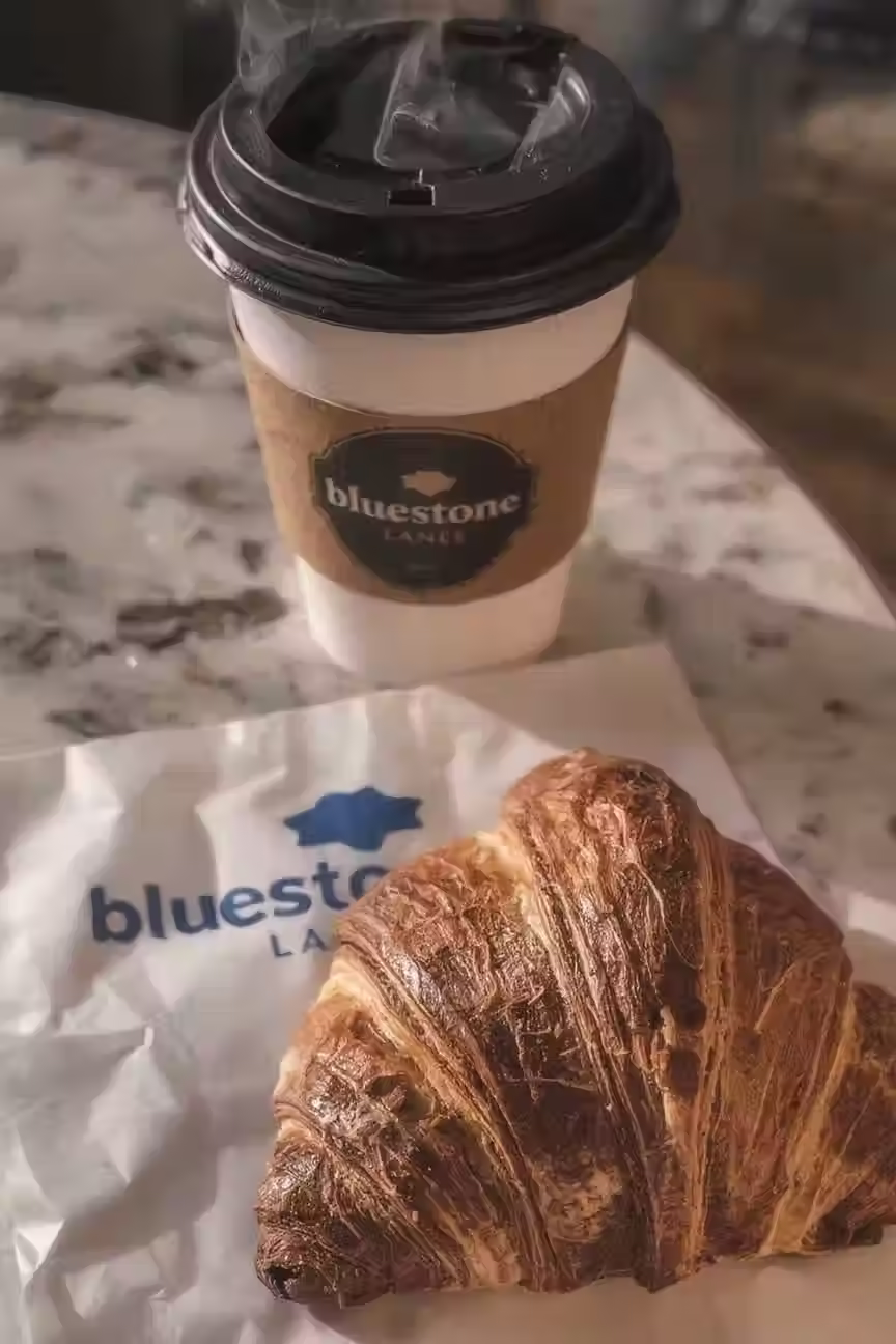 A Photo of the Chocolate Croissant & a To-Go Coffee from Bluestone Lane Rice Village.
