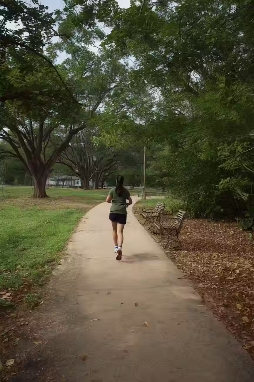 A Photo of a Runner on a Paved path at Dennis Johnston Park. 