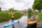 Frau paddelt auf einem Kanal in Friesland