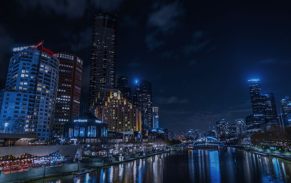 A city on the edge of a riverbank, with a city skyline in the background