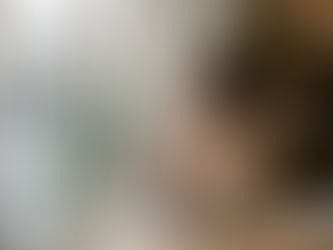 Woman at a cafe table with her phone face down beside her coffee, looking out the window.