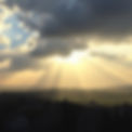 Abstract sunlight rays breaking through clouds over a small town – hopeful tone.jpg