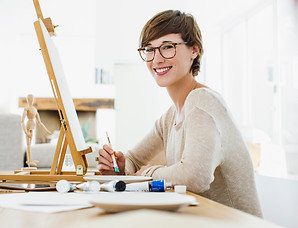 Woman at desk painting a canvas