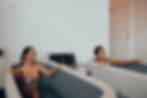 Two women are sitting in separate inflatable ice bath tubs, smiling and looking towards each other