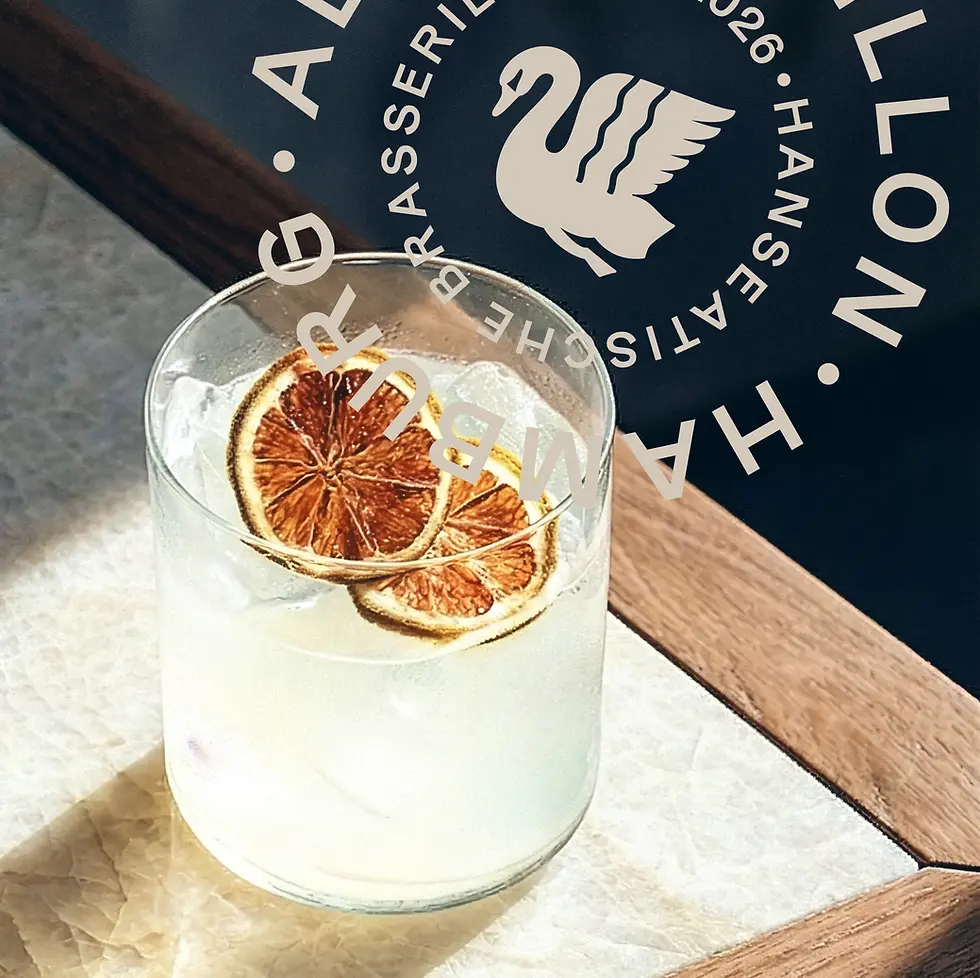 Ein kühler Cocktail mit Eis und zwei getrockneten Zitronenscheiben auf einem hellen Tisch, überlagert vom kreisförmigen Logo der Hanseatischen Brasserie Alsterpavillon.