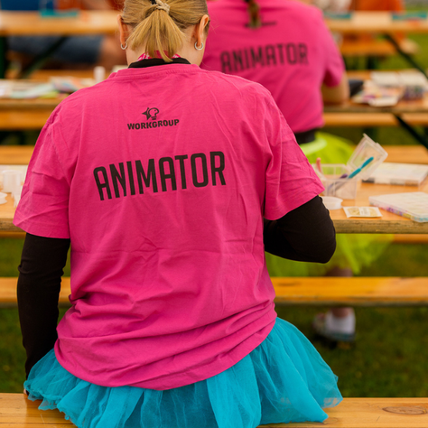 Animatorka maluje twarz dziecku w strefie animacji podczas pikniku firmowego.