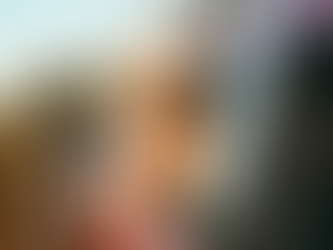 Golden retriever with a happy expression leans out of a red car window on a rural road, under a clear sky.