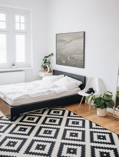 Minimalist bedroom with geometric rug and white bedding