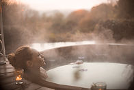 Woman relaxing in a hot tub, surrounded by the serene garden of Arrivée.