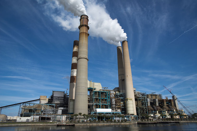 Industrial power plant with tall chimneys and white plumes.