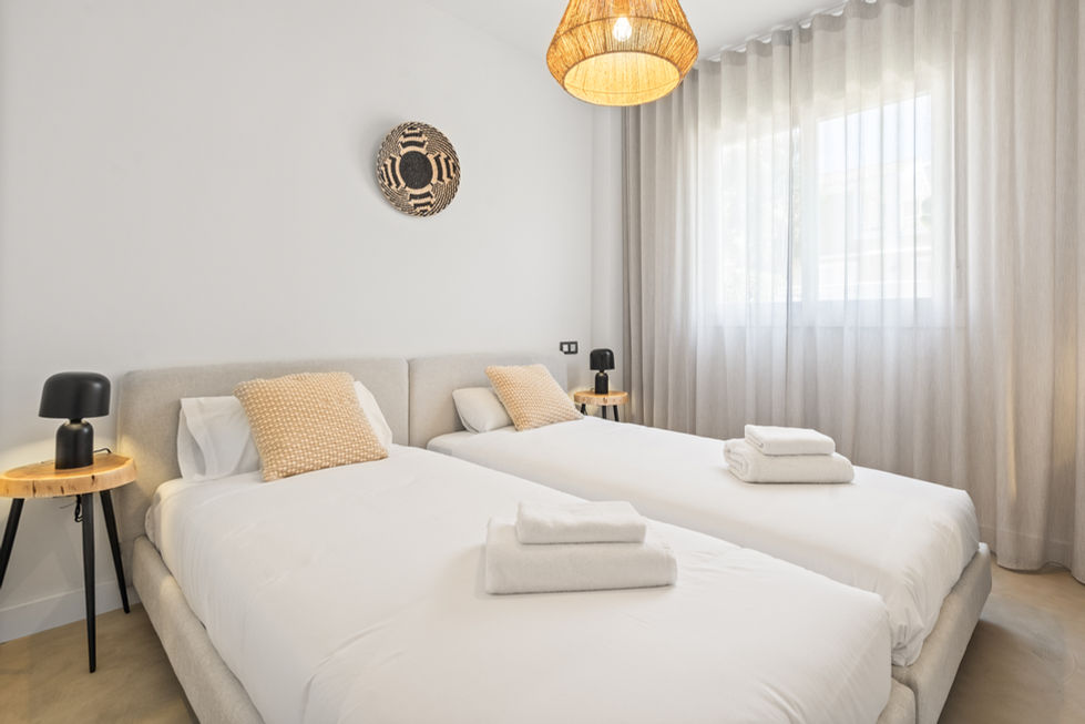 a bedroom with two beds and a lamp hanging from the ceiling