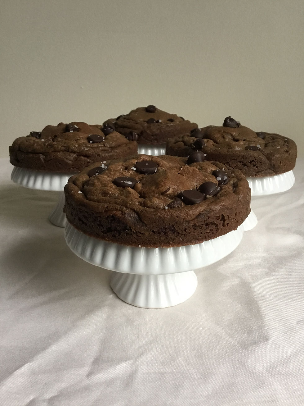 Side view of thick chocolate chocolate chip cookies, sprinkled with coarse salt.