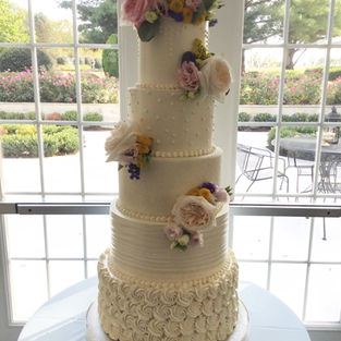 5 Tier all white buttercream wedding cake decorated with fresh flowers.