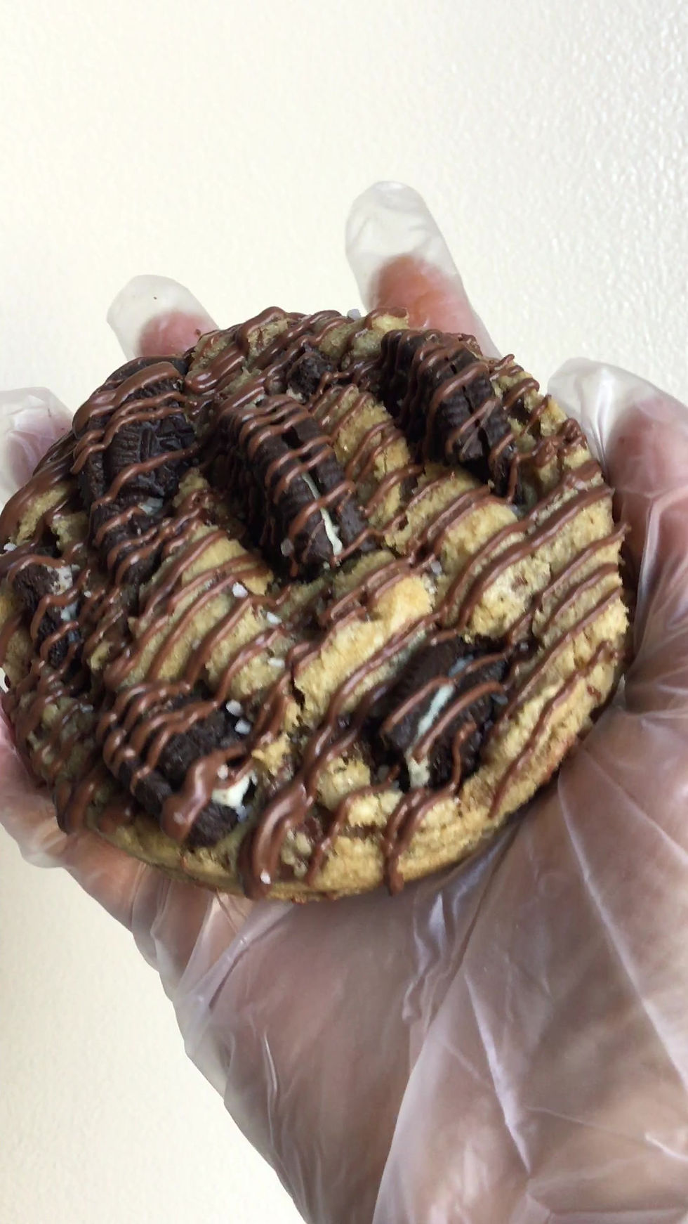 Thick chocolate chip cookies with Oreo cookie pieces and chocolate drizzle close up view