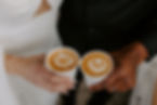 Bride and groom holding custom lattes with love-themed foam art from wedding coffee cart in Portland