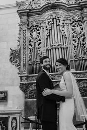 Bride and groom smiling. They are standing in front of a baroque organ.
