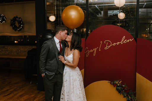 Bride and groom kissing in front of their custom made backdrop.