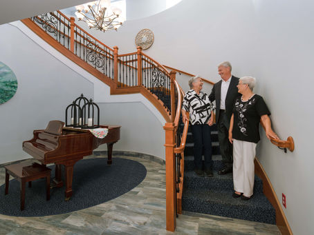 A mother smiling at her son and daughter-in-law at Victoria Landing on the stairs in the lobby.