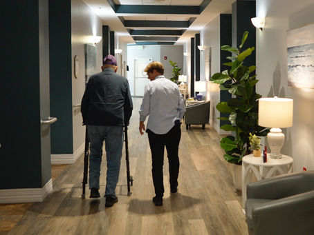 Resident walking with care team in the Boardwalk Memory Care at Victoria Landing.